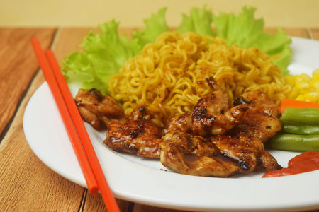 Fried noodles with black pepper seasoned Chicken Steak look tempting on a wooden table. this food is a very unique blend but the taste is very extraordinaryの写真素材