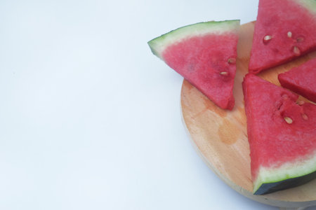 Four slices of watermelon are on a wooden base and isolated white backgroundの写真素材