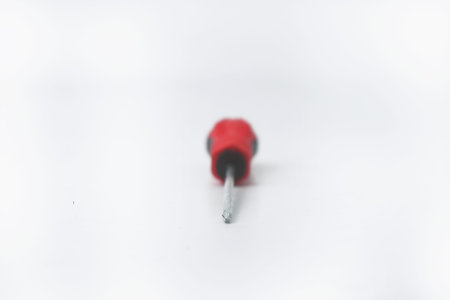 Closeup photo from the front of a red screwdriver often used by craftsmen on an isolated white backgroundの写真素材