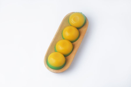Photo seen from above of a round, yellow-green layered cake in a wooden bowl, a traditional...