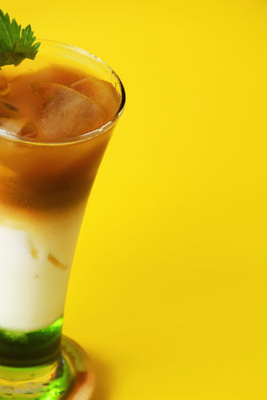 Closeup photo of a pandan iced coffee drink layered with melon syrup, milk and chocolate coffee in a...