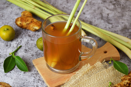 Closeup photo of a healthy hot drink of ginger with lemon and honey in a glass cup with a cement backgroundの写真素材