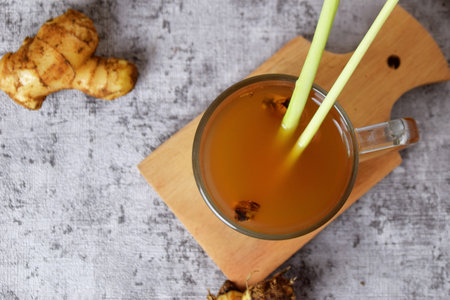 Top view photo of a healthy hot red ginger drink with a mixture of lemon and honey in a glass cup with a cement backgroundの写真素材
