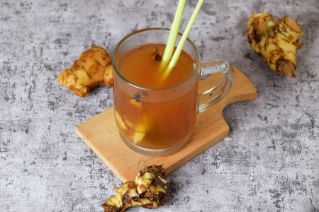 Healthy hot red ginger drink with a mixture of lemon and honey in a glass cup with a cement...