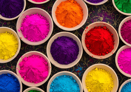 A high-angle close-up view of various vibrant Holi colors in small, shallow white bowls. Generative Aiの素材