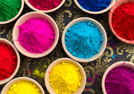 A high-angle close-up view of various vibrant Holi colors in small, shallow white bowls. Generative Aiの素材