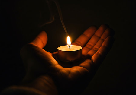 Close-up of a hand holding a small tea light candle in a dark setting. Generative Aiの素材