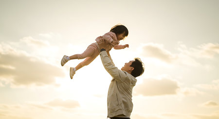 A heartwarming image of a father lifting his young daughter high into the air, creating a moment of pure joy and connection. Generative Aiの素材