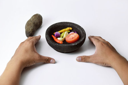 A man shows the ingredients for making chili sauce using cayenne pepper, onions and tomatoes in a...