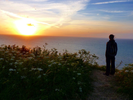 Woman watch sunset on cliff of atlantic ozean in Normandy France
