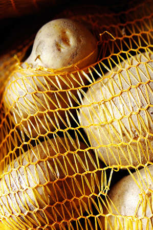 Potatoes in a yellow strucktured sackの写真素材