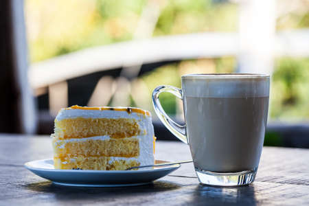 Yellow cake with cup of latte coffee on old wood tableの写真素材