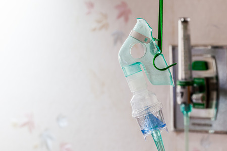 Close-up image of a medical oxygen mask and valve setting blurry on wallの写真素材