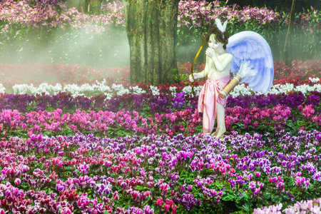 Cupid stand on the flower garden and water spray at night garden