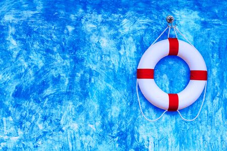 Life buoy hanging on blue polished plaster wallsの写真素材