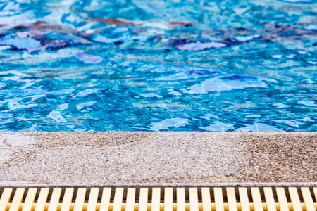 Pool edge with blue water and the overflow drainの写真素材