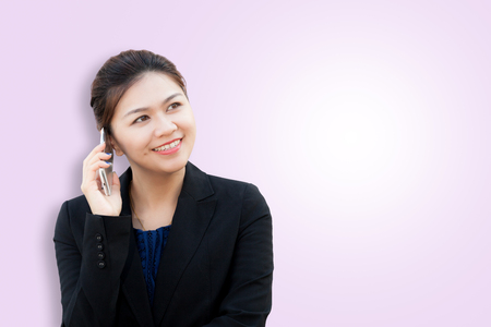 Portrait of smiling business woman using phone on pink background with copy spaceの写真素材