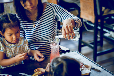 Young mother is brew drinks with daughter in cafeの写真素材