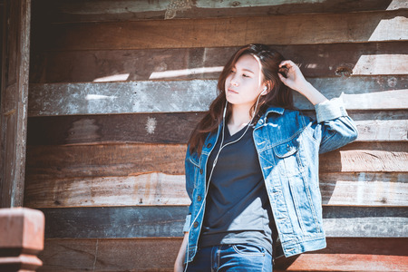 Happy youth teenage using and listening music on smartphone with old wood wall.の写真素材