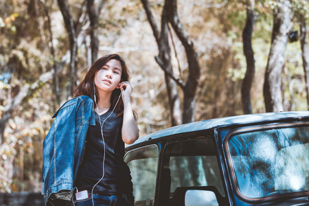 Happy asian youth teenage using and listening music on cellphone with retro car.の写真素材
