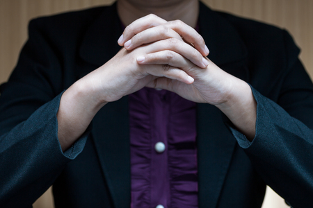 Businesswoman in suit sitting at a desk and clasp her handの写真素材