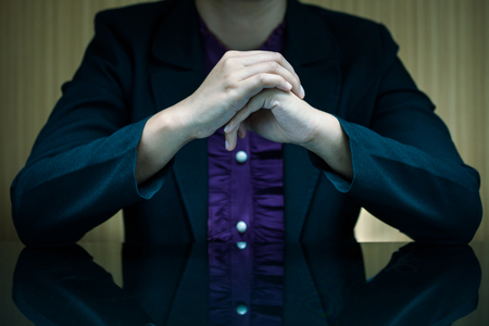 Businesswoman in suit sitting at a desk and clasp her handの写真素材