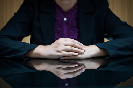 Businesswoman in suit sitting at a desk and clasp her handの写真素材