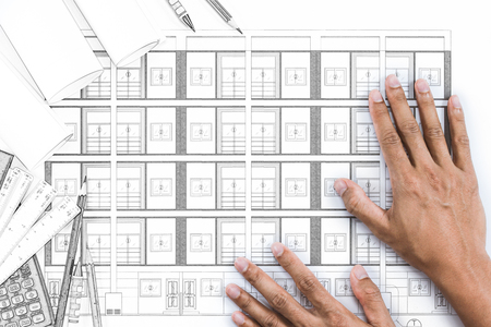Close-up of person engineer hands on blue print with architect instrument at office desk.の写真素材