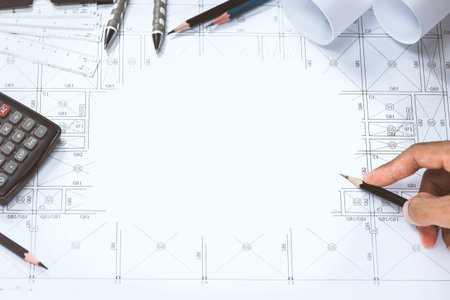 Close-up of person engineer hand drawing plan on blue print with architect instrument at office...