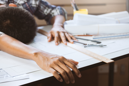 Close-up of hand businessperson having a nap on desk in workspace. Concept of builder working on house project.の写真素材