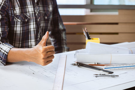 Close-up of confident engineer male showing thumbs up in workspace. Concept of builder working on...