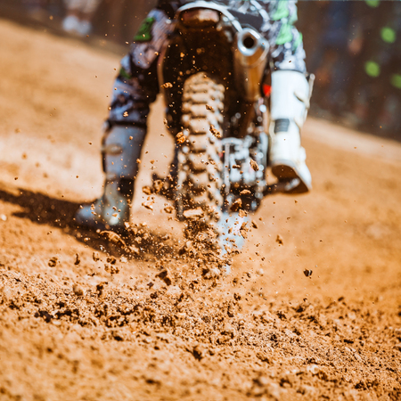 Details of flying debris during an acceleration with mountain bikes race in dirt track in sunshine day time in blurry background. Concept of focus between an accelerate in action sportの写真素材