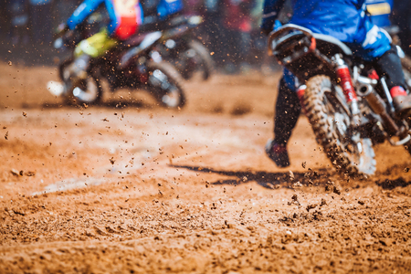 Details of flying debris during an acceleration with mountain bikes race in dirt track in sunshine day time in blurry background. Concept of focus between an accelerate in action sportの写真素材