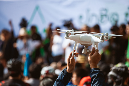 Young operator holding drone above crowd, before working with covering an eventの写真素材