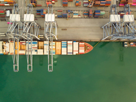 Aerial drone view above dockyard. Cargo vessel is loading containers. Professional business...