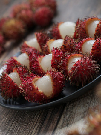 Rambutan on a black plate. Rambutan is a popular fruit in asia. Rambutan tropical and asian fruits, sweet and Delicious, healthy food contain vitamin and nutritionの写真素材
