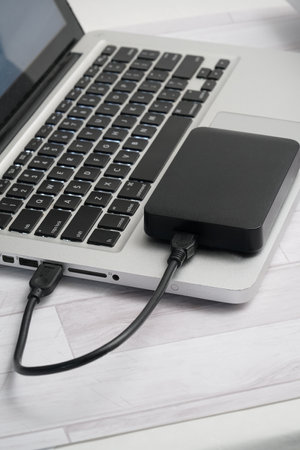 External hard drive connected to a laptop computer with a black power bankの写真素材