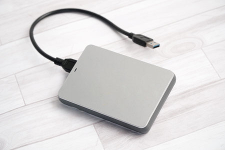 External hard drive with USB cable on a white wooden background. Top view.の写真素材