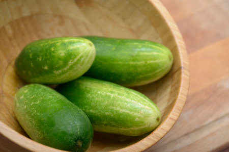 Cucumbers in a wooden bowl on a wooden background. Selective focus.の写真素材