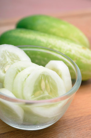 Cucumber slices in a glass bowl on wooden table. Selective focus.の写真素材