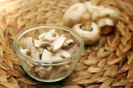 Champignon mushrooms in a glass bowl on a wicker backgroundの写真素材