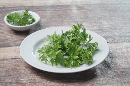 Fresh parsley on a white plate, on a wooden table.の写真素材