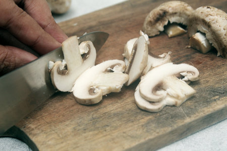Sliced champignon mushrooms on a cutting board with a knifeの写真素材