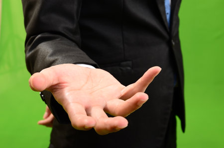 Businessman holding his hand out for a handshake on a green backgroundの写真素材