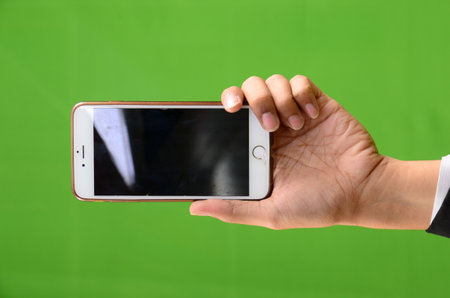 male hand holding smart phone with green screen on the green background.の写真素材