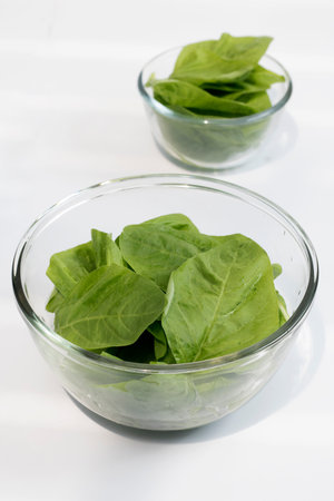 Fresh spinach leaves in glass bowl on white background. Selective focus.の写真素材
