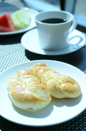 Breakfast with coffee and buns on table in morning light.の写真素材