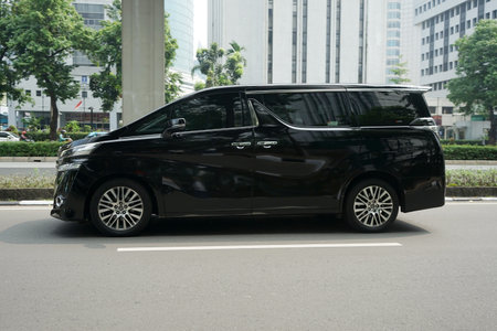 Luxury Multi Purpose Vehicle (MPV) car, black Toyota Alpard on the road at commercial and business distric Rasuna Said Street, Jakarta, Indonesiaのeditorial素材