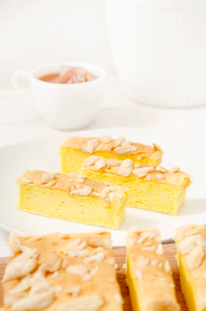 Slices of soft cake with almond and a cup of tea on white backgroundの写真素材