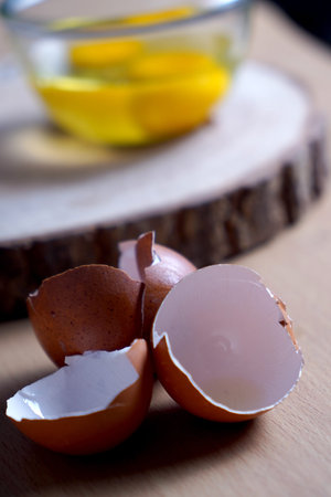 Broken eggshell on a wooden board with lemon and honey in the background